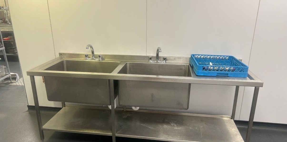 Twin-basin stainless-steel commercial sink station reinstalled by AJL after new pipework fitted